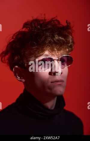 Young Man Wearing Sunglasses against Vibrant Red Background Stock Photo