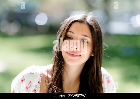 Close up happy smiling beautiful young latina teenager teen female seated park Stock Photo