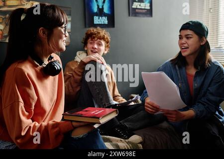 Group of students collaborating on project, sitting and discussing in casual room setting, wide smiles and positive energy Stock Photo