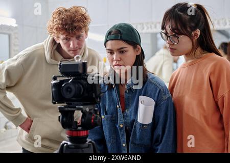 Group of young adults collaborating on creative project in indoor setting, involving filming process with professional camera equipment Stock Photo