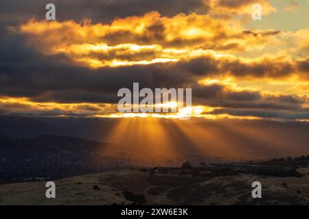 Sun setting and beaming through clouds at Santa Teresa County Park, Santa Clara County, California. Stock Photo