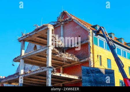 Building is being demolished in the city. Crane operates on a building undergoing demolition, showcasing the construction process in action Stock Photo