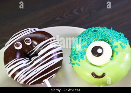 Plate of Halloween Mummy and Monster Donuts Isolated on Black Wooden Background Stock Photo