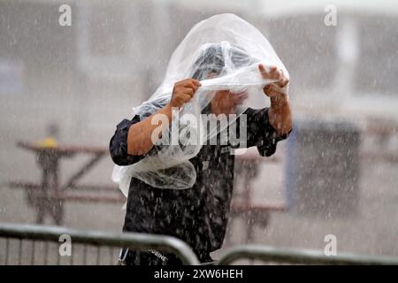 A security person is protecting himself from the rain at Woodbine Racetrack in Toronto, Canada, on August 17, 2024. Canada's premiere thoroughbred horse race, The King's Plate, is being cancelled for horse safety due to excessive rainfall on track surfaces. (Photo by Mike Campbell/NurPhoto)0 Credit: NurPhoto SRL/Ģ����ý Live News Stock Photo