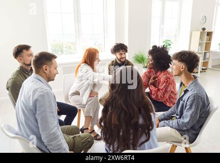 Young diverse business people in casual clothes discussing work project sitting in circle in office Stock Photo