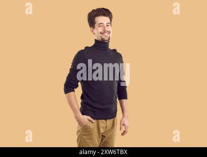 Portrait of happy confident brunet guy in black turtleneck on beige background looking at camera. Stock Photo
