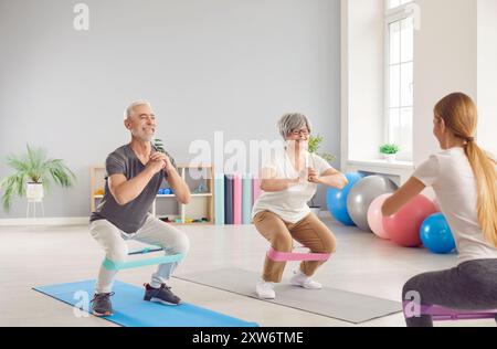 Active happy elderly people, seniors exercising with coach, using fitness rubber band, health care  Stock Photo