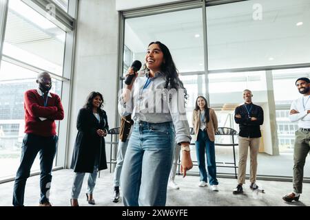 Group of young corporate employees engaging in a team building event with a dynamic speaker. Diverse team in a modern office setting. Stock Photo