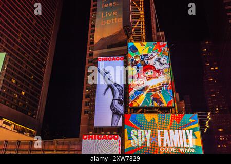 Broadway, New York at night with skyscrapers featuring LED billboards for 'Chicago' and 'Space Family' musicals. New York. USA. Stock Photo