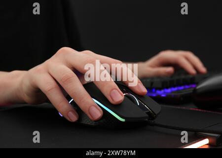 Gamer using modern wired computer mouse at dark table, closeup Stock Photo