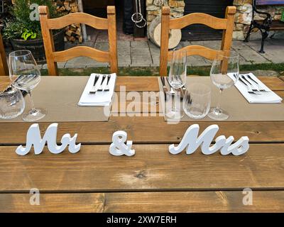 Table prepared for a dinner for the newlyweds at a wedding party in a beautiful garden. Mr and Mrs decorations. Summer afternoon. Modra, Slovakia. Stock Photo