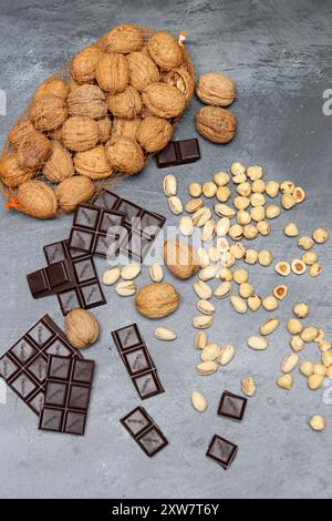 Chocolate bars, walnuts and hazelnuts on a gray background. Stock Photo