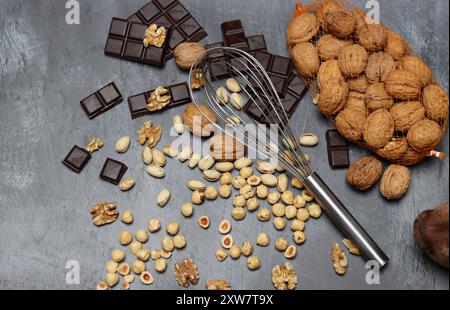 Chocolate bars, walnuts and hazelnuts on a gray background. Stock Photo