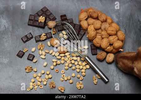 Chocolate bars, walnuts and hazelnuts on a gray background. Stock Photo
