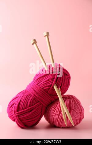 Different yarns and knitting needles on pink background Stock Photo