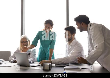 Multiethnic laughing internists using laptop in conference room Stock Photo