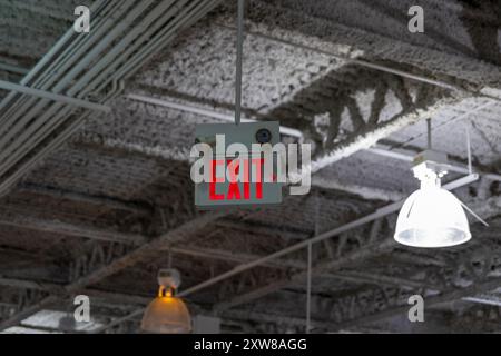 Exit sign with white lettering and right arrow - hanging from industrial ceiling. Taken in Toronto, Canada. Stock Photo