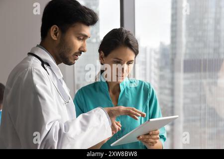 Multiethnic doctors focusing on tablet engaged in collaborative medical consultation Stock Photo