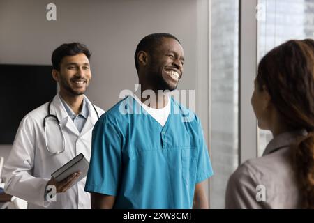 African doctor in blue scrubs laughing during talk with patient Stock Photo
