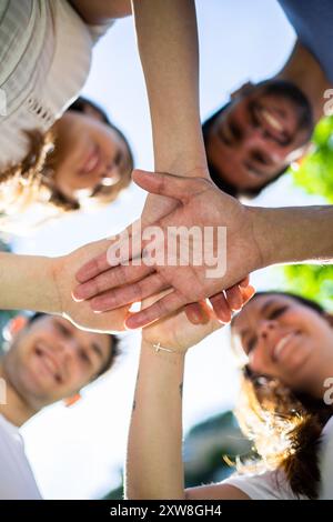 Group of diverse friends stacking hands in a gesture of unity and support Stock Photo