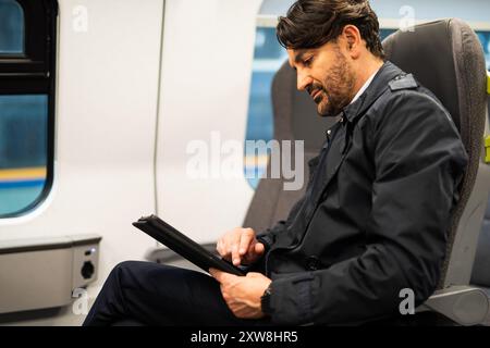 Professional man engages with a digital tablet while commuting on a train Stock Photo