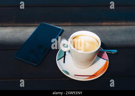 A cup of coffee and mobile phone on wooden table, close up. Stock Photo