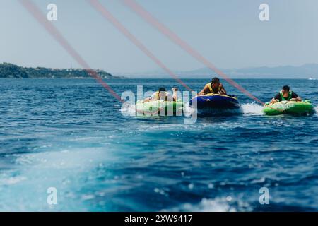 Friends enjoying a thrilling speedboat tubing adventure on a sunny summer day Stock Photo