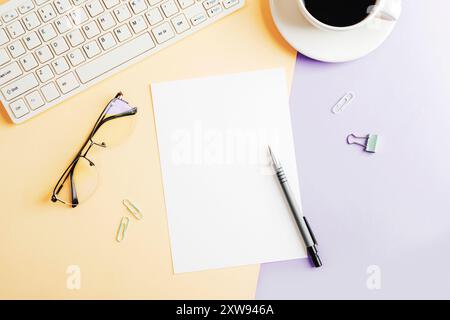 Desktop with blank paper, computer keyboard, glasses and coffee cup on beige and purple two-colored background. Top view, flat lay, mockup. Stock Photo