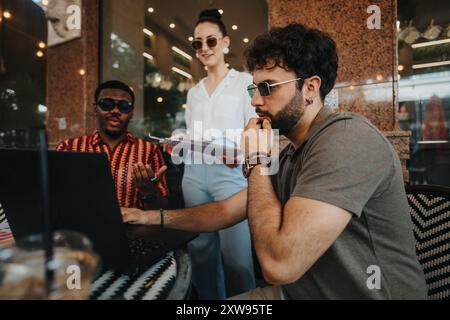 Diverse business team collaborating on project outdoors with laptop and documents Stock Photo
