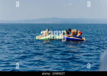 Friends enjoying a thrilling speedboat tubing adventure on a sunny day Stock Photo