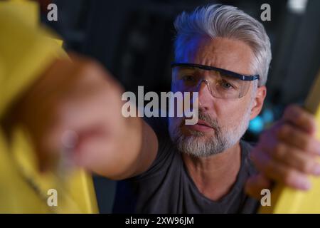 Automation engineer checking, servicing robotic arm. Concept of modern technology in industries, automated processes, robotics. Stock Photo