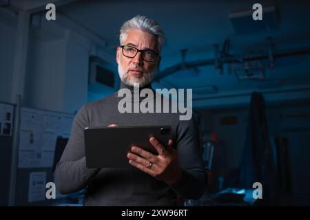 Automation engineer, technician holding remote controller of robotic arm. Concept of modern technology in industries, automated processes, robotics. Stock Photo