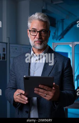 Portrait of robotics engineer holding tablet, looking at camera. Concept of modern technology in industries, automated processes, automotive Stock Photo