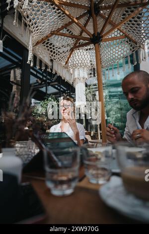 Business workers collaborating on a project in a coffee bar, brainstorming ideas under an outdoor umbrella Stock Photo