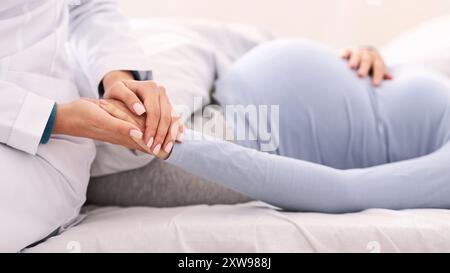 Unrecognizable Doctor Holding Pregnant Woman's Hand Indoor Stock Photo