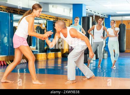 Young woman practicing supinating wristlock with man in self-defense course Stock Photo