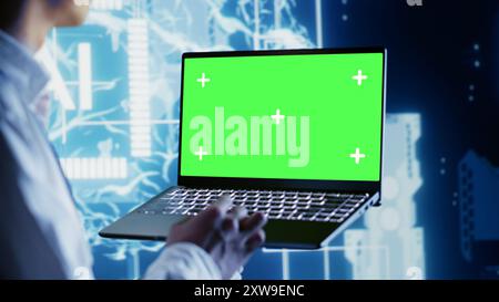 Computer scientist using chroma key laptop to write artificial intelligence script code in startup workplace. Dilligent worker doing maintenance work in data center, updating AI systems Stock Photo