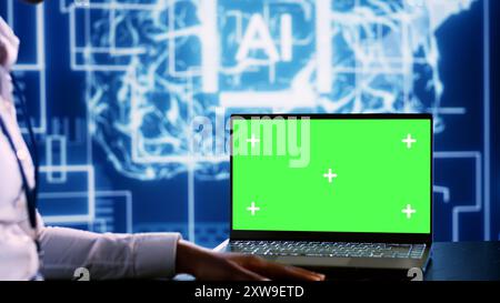 IT executive updating AI systems using green screen laptop, writing intricate binary code scripts. Technical support consultant using programming to upgrade artificial intelligence simulation model Stock Photo