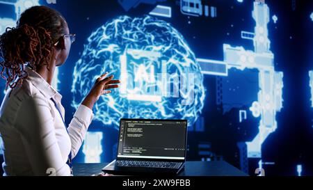 African american IT expert updating AI systems, writing intricate binary code scripts on tablet and laptop. Certified admin using programming to upgrade artificial intelligence simulation model Stock Photo