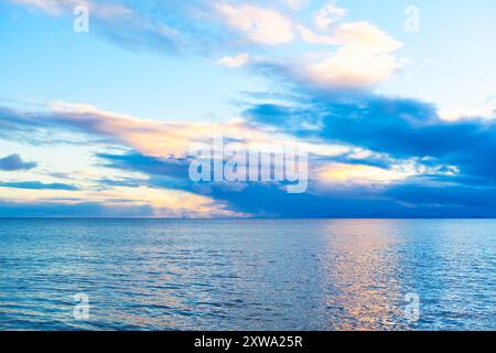 Serene ocean view at sunset, with vibrant colors reflecting off the water and clouds scattered across the sky. Picturesque twilight over the ocean Stock Photo