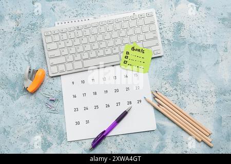 Sticky note with to do plans, computer keyboard and calendar on blue grunge background. New year goals concept Stock Photo