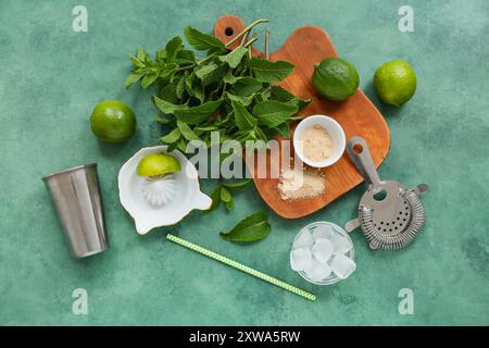 Wooden cutting board, shaker, strainer and ingredients for mojito on green background Stock Photo