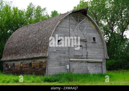 Weathered wooden barn with a peaked roof in a farm yard in north-eastern Saskatchewan Stock Photo