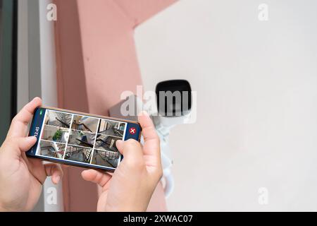 Professional cctv technician working. Person hand holding smartphone with multiple camera views of office locations. Surveillance, modern technology b Stock Photo