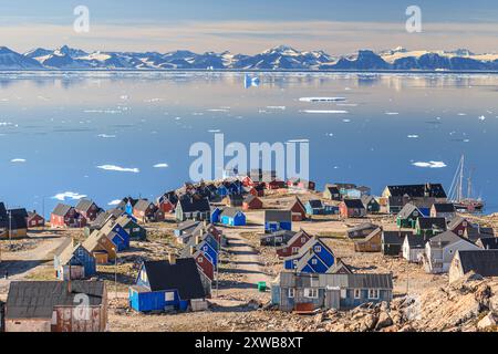 Typical greenlandic houses at a fjord with icebergs and mountains, sunny, Ittoqqortoormiit, Scoresby Sund, East Greenland, Greenland Stock Photo