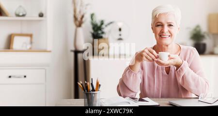 Peaceful aged lady having coffee break while working Stock Photo