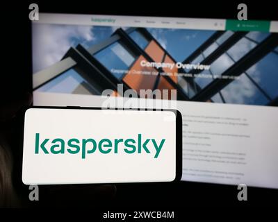 Person holding smartphone with logo of Russian cybersecurity company AO Kaspersky Lab in front of website. Focus on phone display. Stock Photo