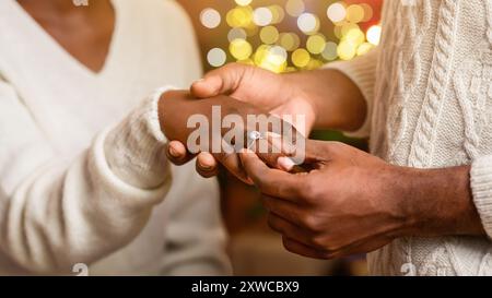 Black man putting ring on girlfriend's finger after proposal Stock Photo