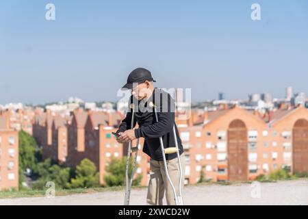 disabled man using his smartphone while walking with his crutches Stock Photo