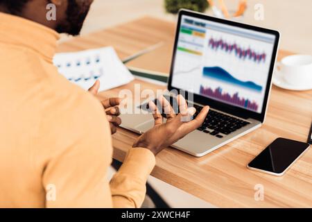 Stressed afro businessman looking at graphs on screen Stock Photo